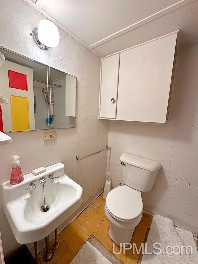 bathroom featuring toilet, tile patterned floors, and sink