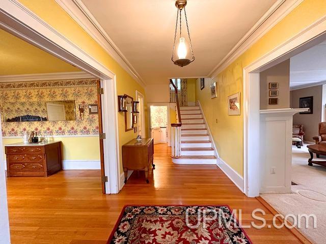 hall with wood-type flooring and ornamental molding