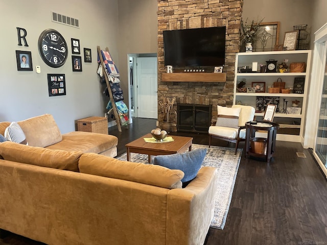 living room with dark hardwood / wood-style flooring and a stone fireplace