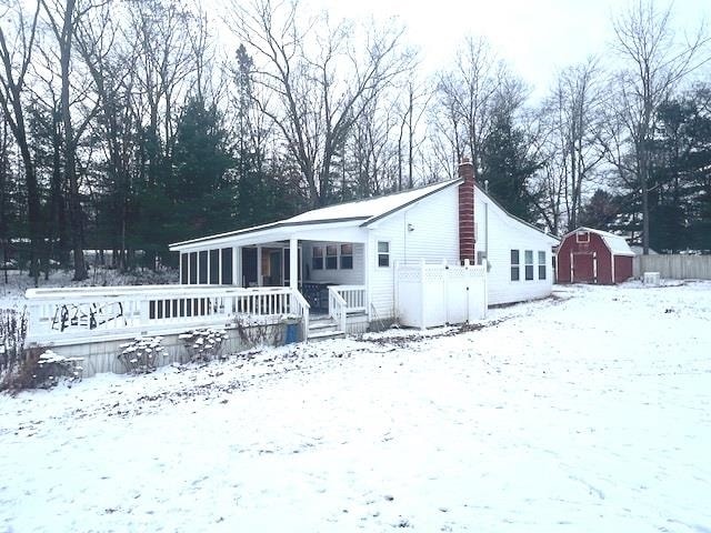 snow covered rear of property featuring a shed