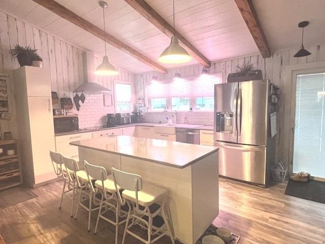 kitchen with a center island, wall chimney range hood, a breakfast bar area, white cabinets, and black appliances