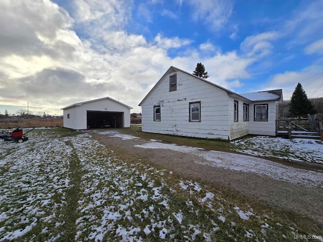 snow covered property featuring a garage and an outdoor structure