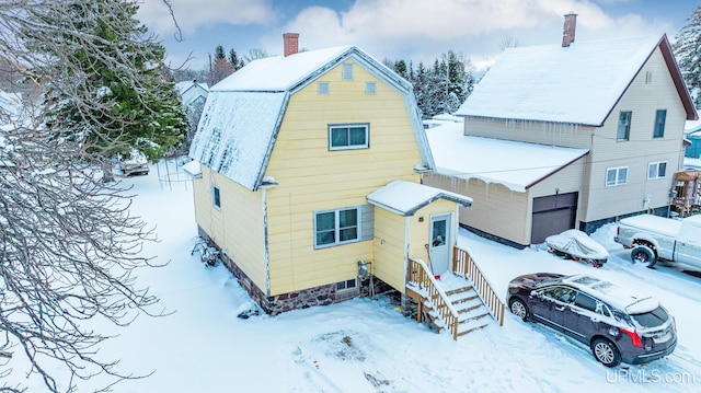 view of front of home featuring a garage, a chimney, and a gambrel roof