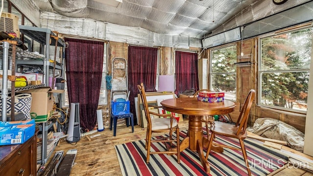 dining room with wood-type flooring, wooden walls, and vaulted ceiling