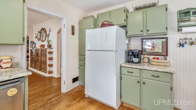 kitchen with green cabinetry, stainless steel dishwasher, light stone countertops, light hardwood / wood-style floors, and white fridge