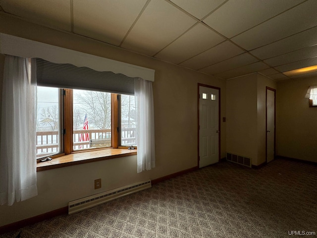 empty room with a drop ceiling, carpet floors, and baseboard heating