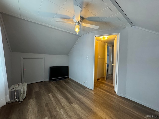 additional living space with an AC wall unit, ceiling fan, dark wood-type flooring, and vaulted ceiling