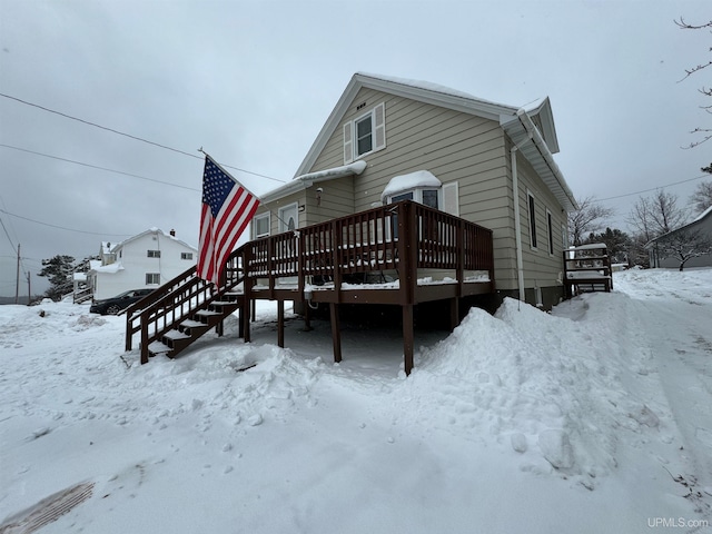 snow covered back of property with a deck