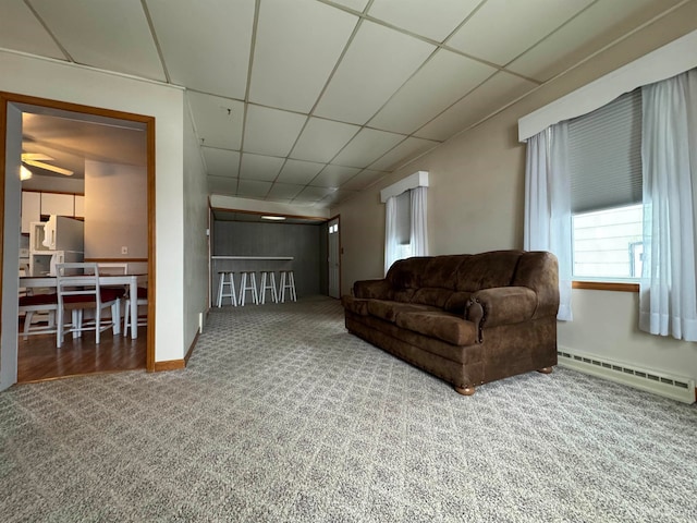 carpeted living room with a paneled ceiling, baseboard heating, and ceiling fan