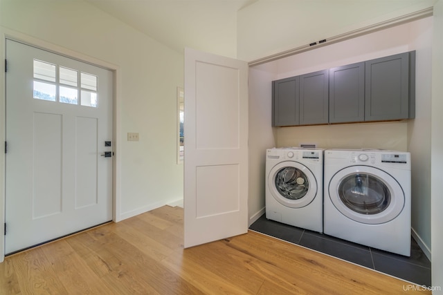 laundry room featuring washing machine and clothes dryer, cabinets, and light hardwood / wood-style floors