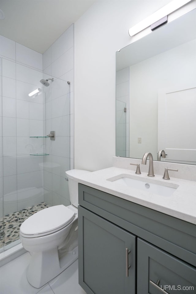 bathroom featuring tile patterned flooring, vanity, toilet, and an enclosed shower