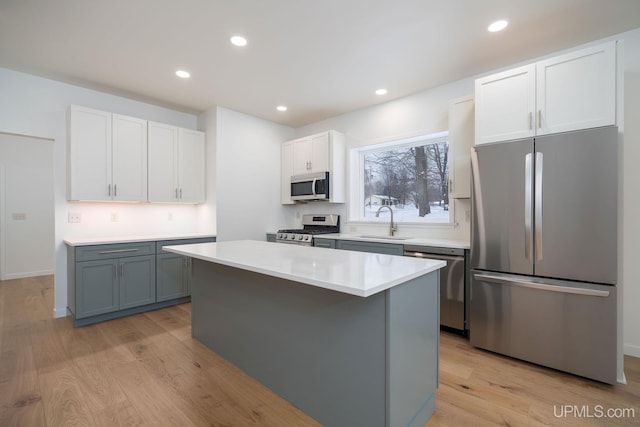 kitchen with white cabinets, gray cabinetry, light wood-type flooring, and stainless steel appliances