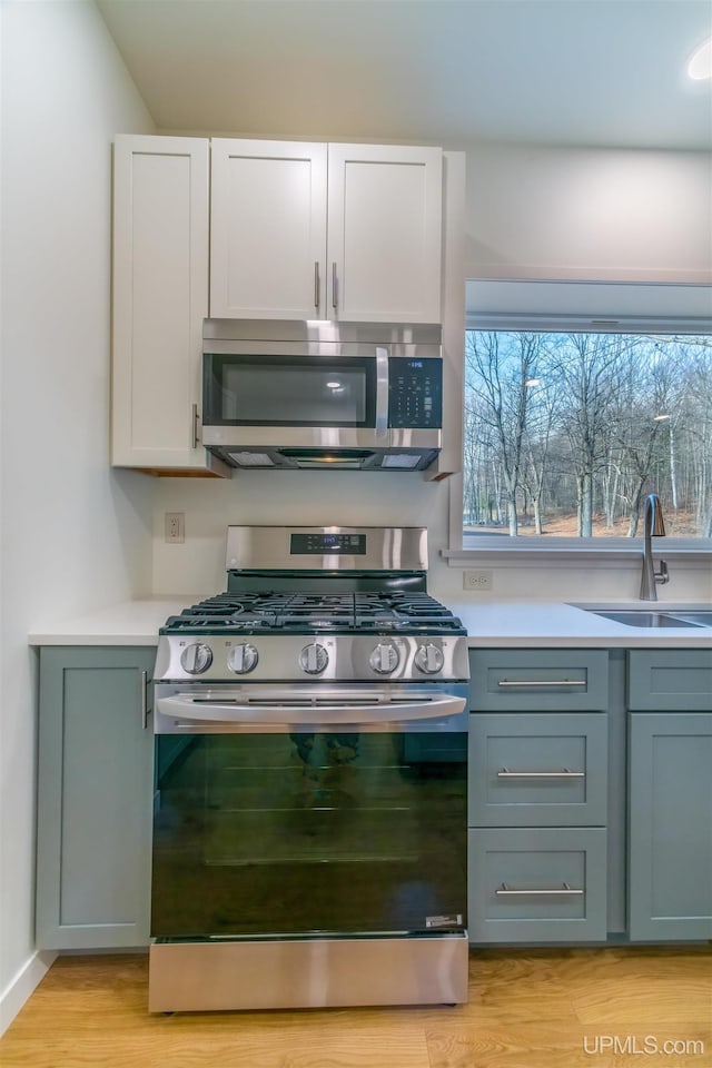 kitchen featuring white cabinetry, sink, stainless steel appliances, and light hardwood / wood-style flooring