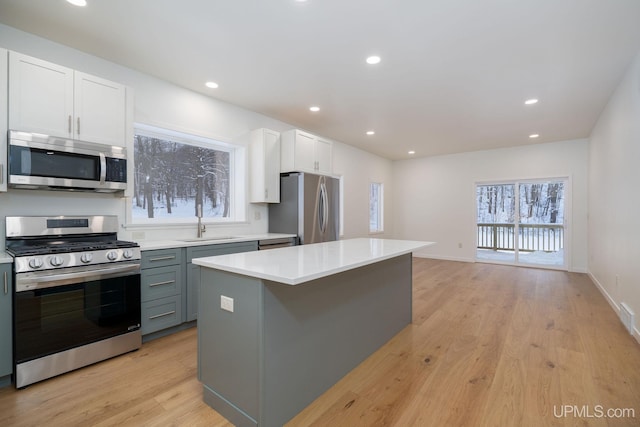 kitchen featuring white cabinetry, a center island, stainless steel appliances, and light hardwood / wood-style flooring