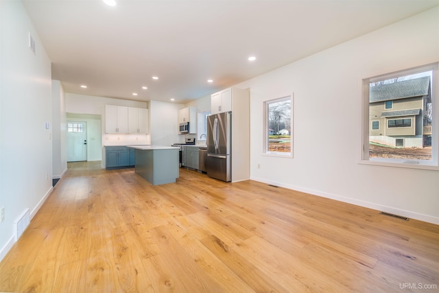 kitchen featuring a kitchen island, light hardwood / wood-style floors, white cabinetry, and appliances with stainless steel finishes