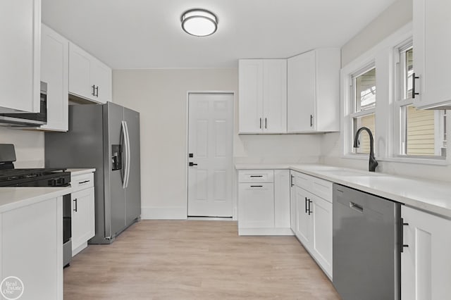 kitchen with light hardwood / wood-style flooring, white cabinets, stainless steel appliances, and sink