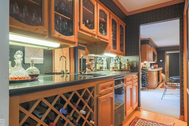 kitchen with sink, light wood-type flooring, and crown molding