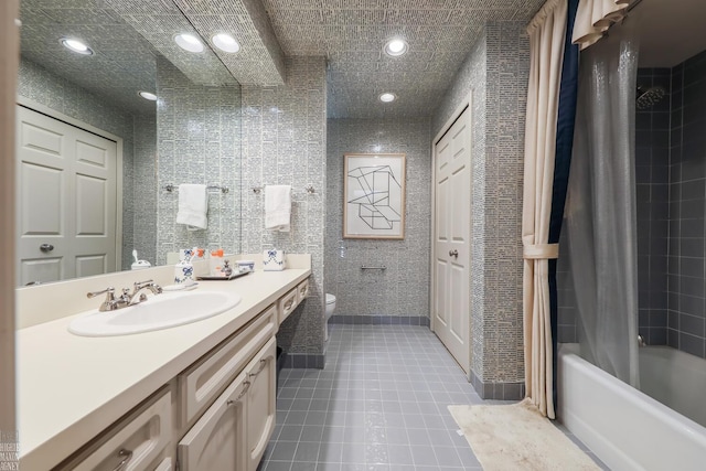 full bathroom with shower / bath combo, tile patterned flooring, toilet, vanity, and tile walls