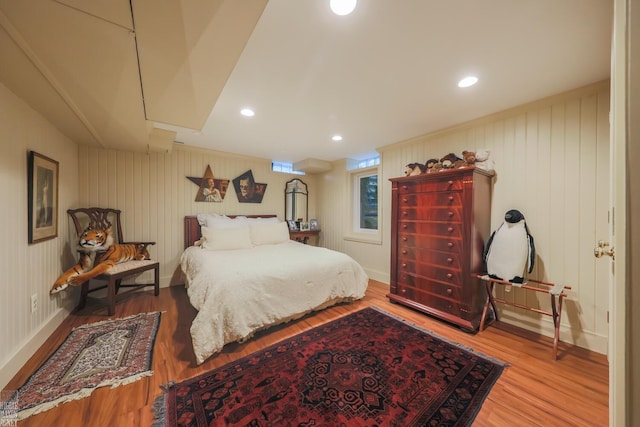 bedroom with hardwood / wood-style flooring and wood walls