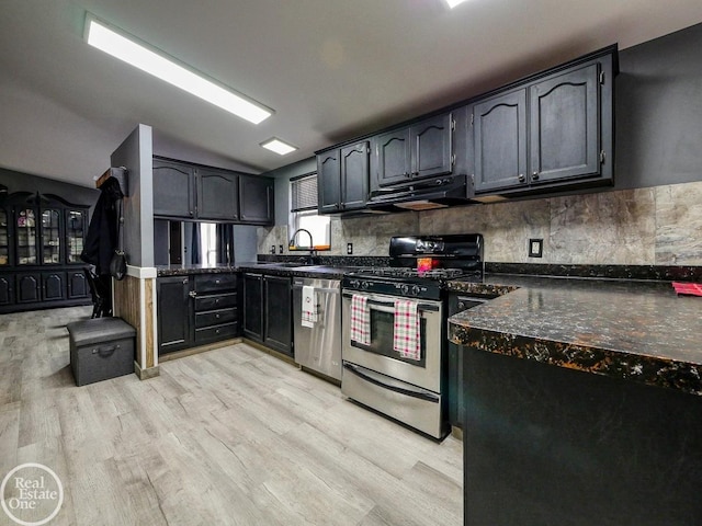 kitchen with stainless steel appliances, light hardwood / wood-style flooring, range hood, dark stone counters, and decorative backsplash