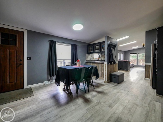 dining space with light hardwood / wood-style floors and vaulted ceiling