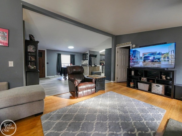 living room featuring vaulted ceiling with beams and hardwood / wood-style flooring