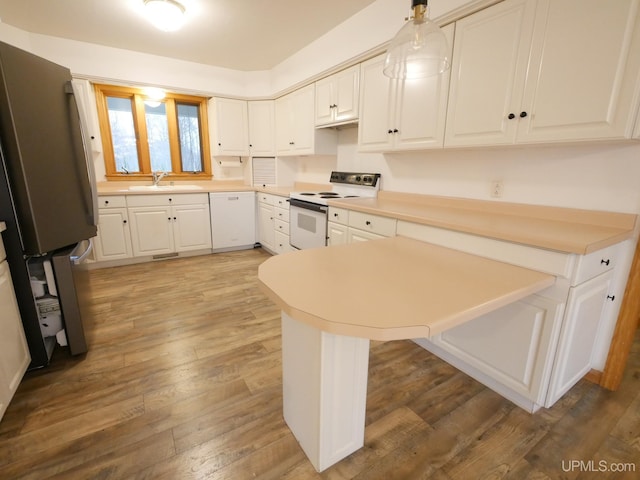 kitchen featuring white appliances, sink, hardwood / wood-style floors, white cabinetry, and hanging light fixtures