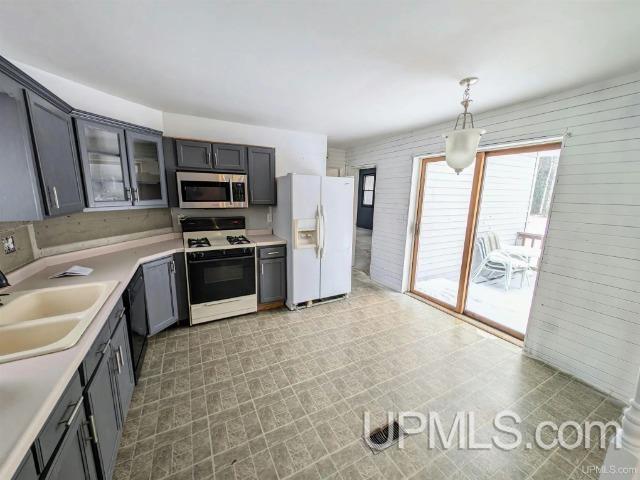 kitchen featuring gray cabinets, sink, hanging light fixtures, and white appliances