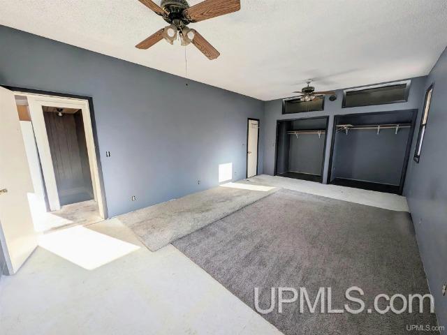 interior space with carpet flooring, ceiling fan, and a textured ceiling