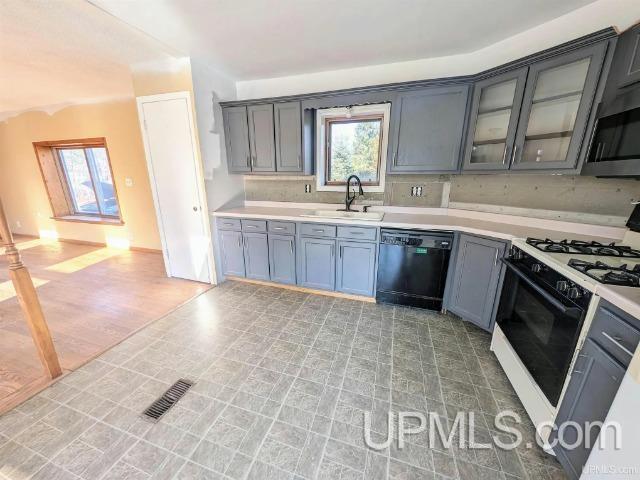 kitchen featuring light wood-type flooring, backsplash, white range with gas cooktop, sink, and black dishwasher