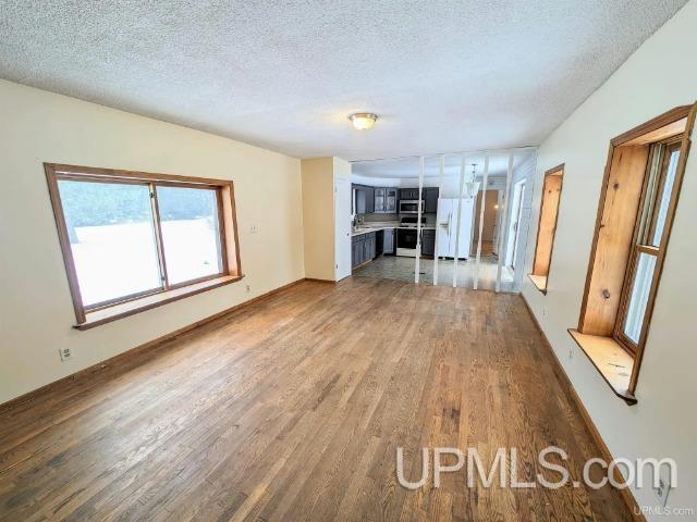 unfurnished living room featuring wood-type flooring and a textured ceiling