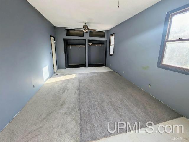 carpeted spare room featuring ceiling fan