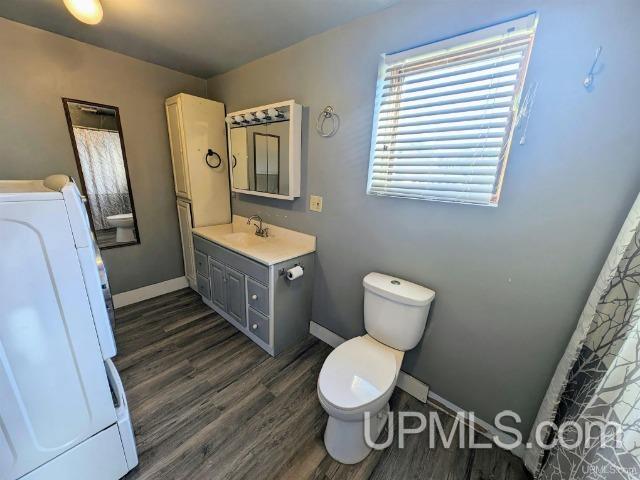 bathroom with wood-type flooring, vanity, washer / clothes dryer, and toilet