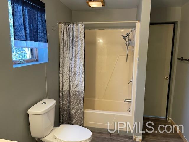 bathroom featuring hardwood / wood-style floors, toilet, and shower / bath combo with shower curtain