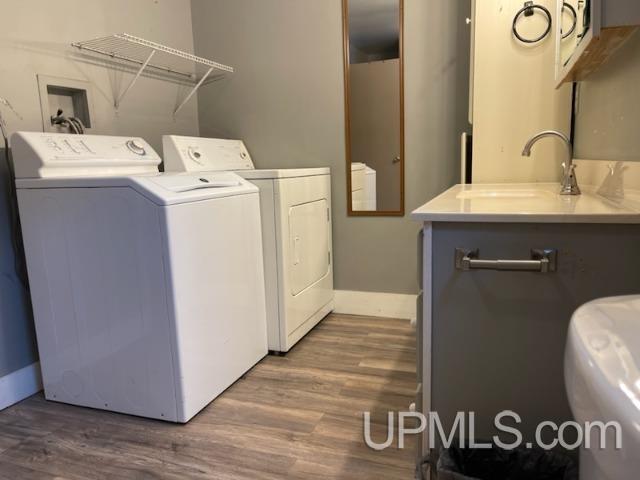 clothes washing area featuring washing machine and dryer, sink, and dark hardwood / wood-style flooring