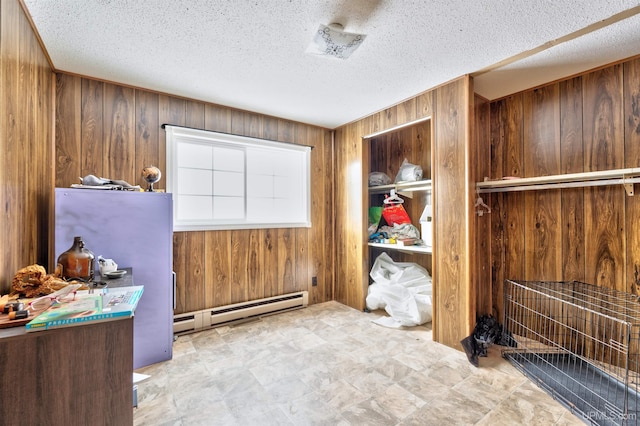 interior space featuring wood walls, a baseboard radiator, and a textured ceiling