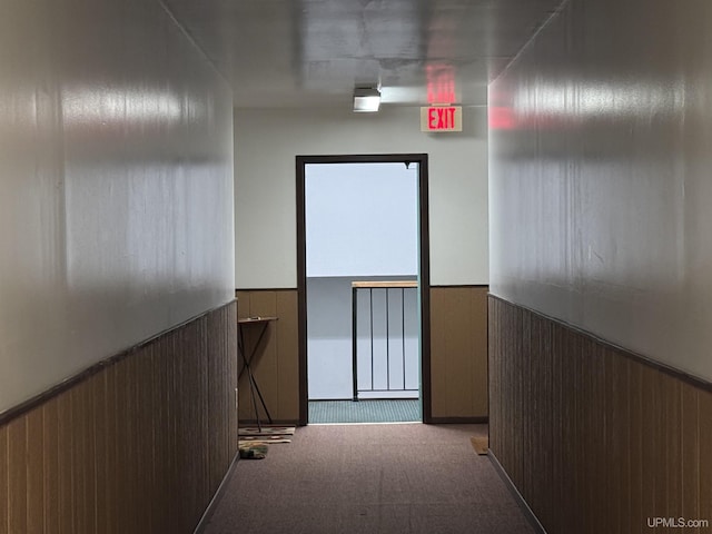 hall featuring wood walls and light colored carpet