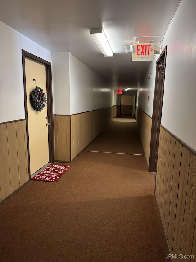 corridor featuring wood walls and light colored carpet