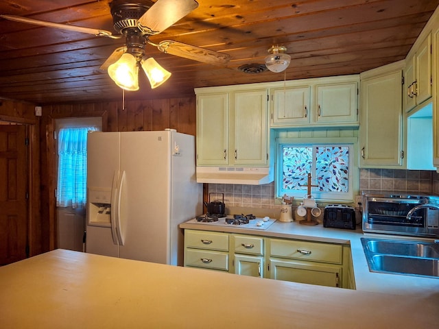 kitchen featuring decorative backsplash, wood walls, white appliances, and sink