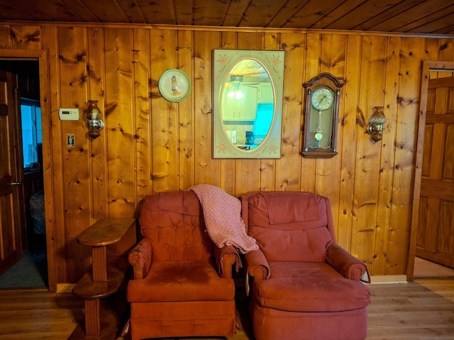 sitting room featuring light hardwood / wood-style floors, wooden ceiling, and wood walls