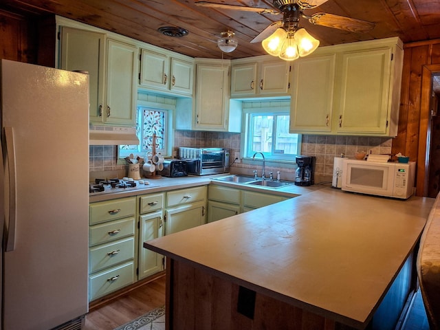 kitchen featuring ceiling fan, sink, wooden ceiling, kitchen peninsula, and white appliances