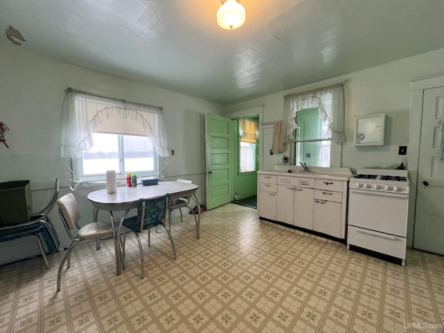 kitchen with sink, white cabinetry, and white gas range oven