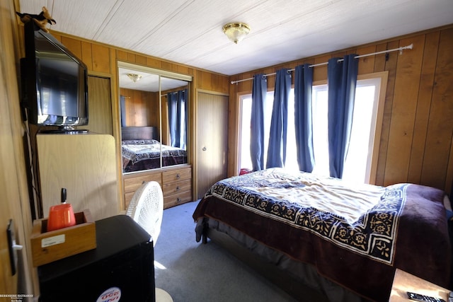 carpeted bedroom with wood walls and a closet