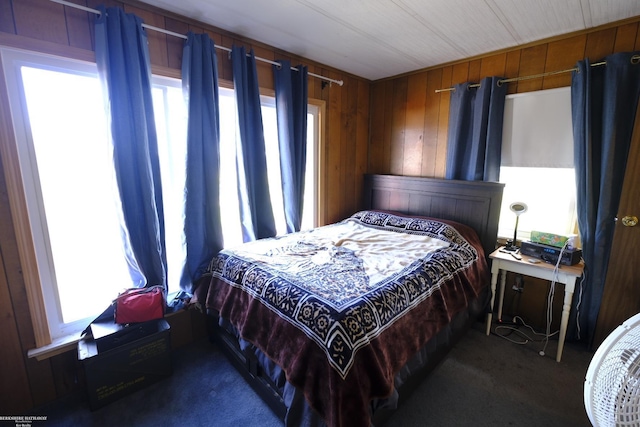 bedroom featuring dark carpet and wooden walls