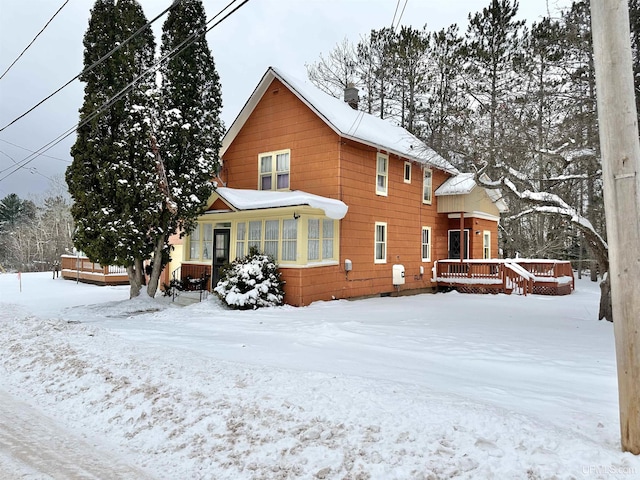 snow covered back of property featuring a deck