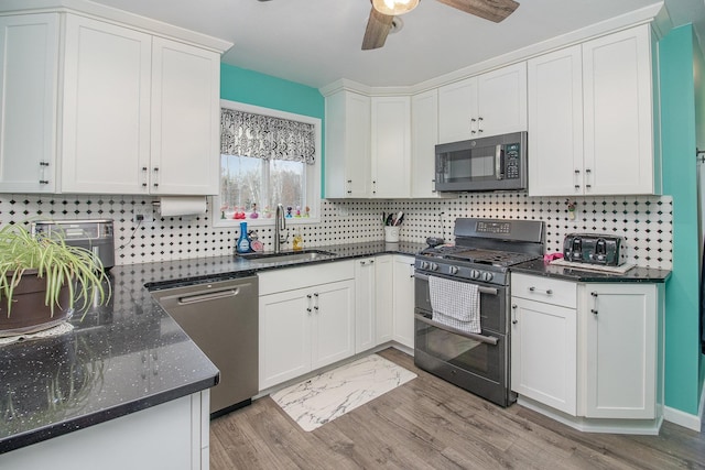 kitchen with decorative backsplash, appliances with stainless steel finishes, light wood-type flooring, sink, and white cabinets