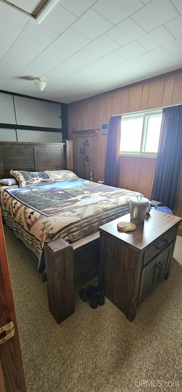 carpeted bedroom featuring wooden walls