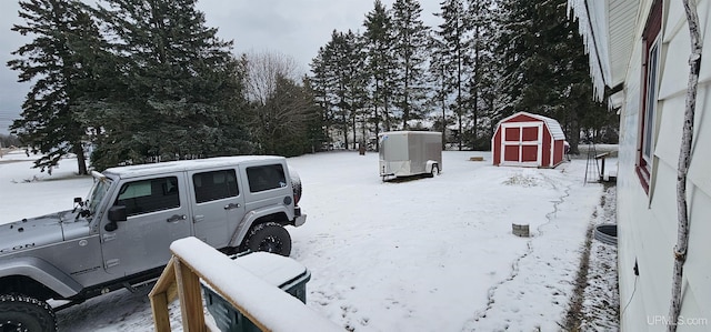 yard layered in snow featuring a shed