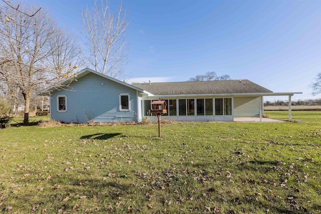 rear view of house featuring a lawn, a sunroom, and a patio