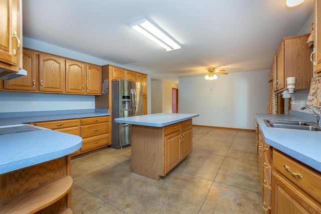 kitchen featuring sink, stainless steel refrigerator with ice dispenser, ceiling fan, white cooktop, and a kitchen island